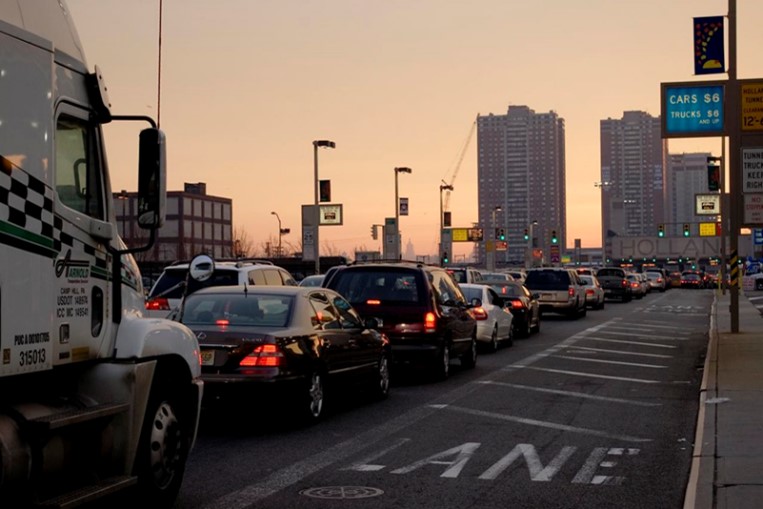 Cars and trucks in heavy traffic entering a city